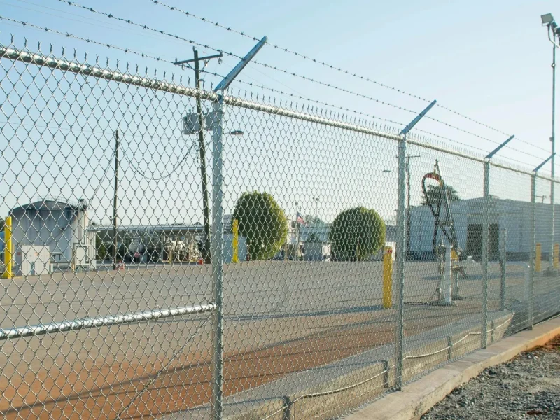 Chain link fence with barbed -wire outrigger
